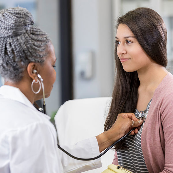 Teenage girl receives checkup at doctor
