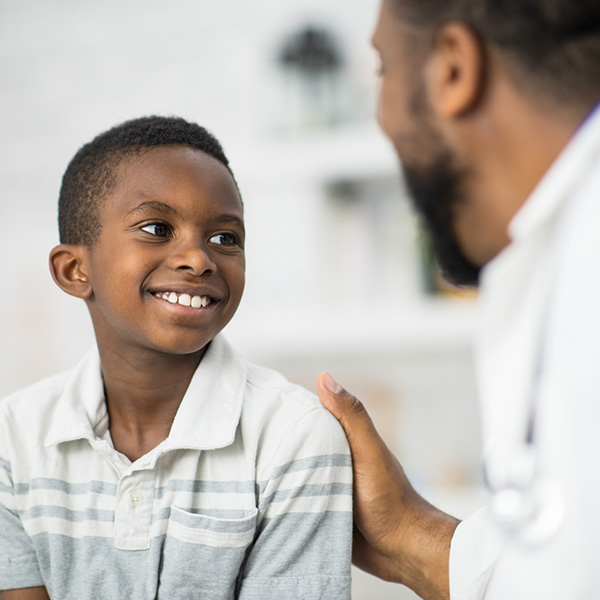 young boy o sits up on an exam table