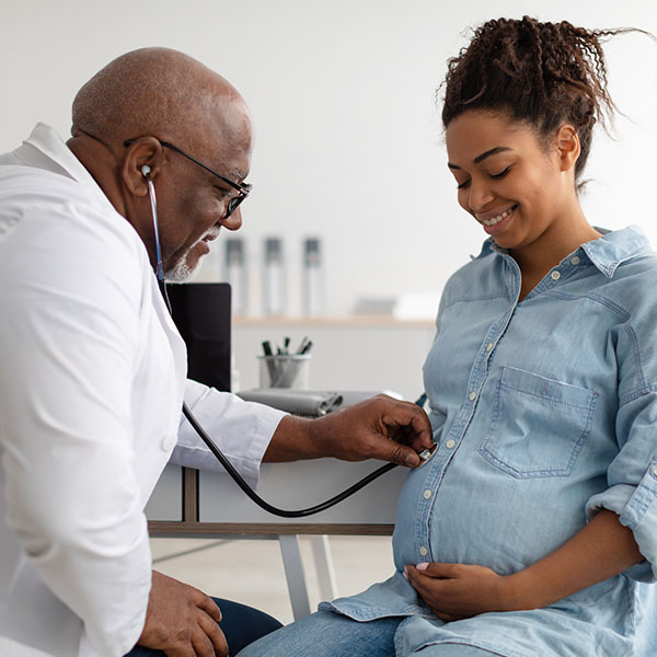Male experienced doctor examining young pregnant woman